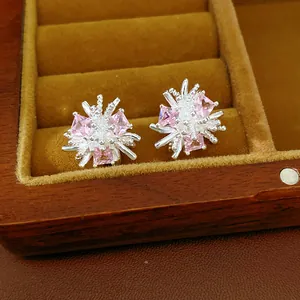 Gros plan détaillé de boucles d'oreilles fleur en argent avec des oxydes de zirconium roses.