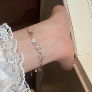 Close-up of elegant zircon butterfly and shell flower anklet on ankle with lace background.