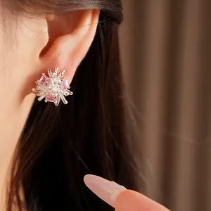 Gros plan d'une boucle d'oreille en argent avec un motif de fleur en zircone rose