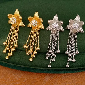 Detailed macro view of 18k gold and silver flower tassel earrings with zircon inlay