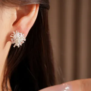 Gros plan professionnel de boucles d'oreilles fleurs en zircone sur l'oreille d'un modèle