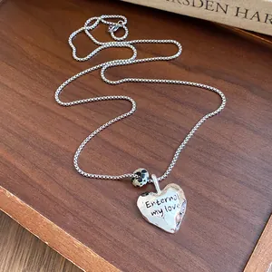 Dettaglio della collana con pendente a cuore d'argento con perla in pietra e dedica