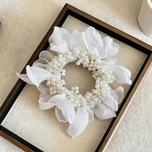 Elegant white chiffon flower scrunchie adorned with pearls presented in a classic wooden frame