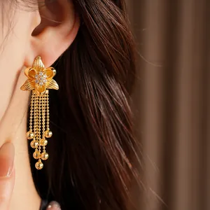 Macro view of 18k gold-plated flower earring featuring cubic zirconia and bead tassels