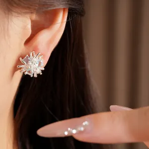 Vue macro d'une boucle d'oreille fleur en argent avec zircon bleu sur une oreille