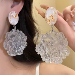Detailed view of elegant clear resin flower earrings with gold foil inlaid oval studs