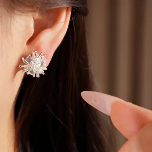 Gros plan d'une boucle d'oreille fleurie en argent avec zircons bleu clair sur l'oreille