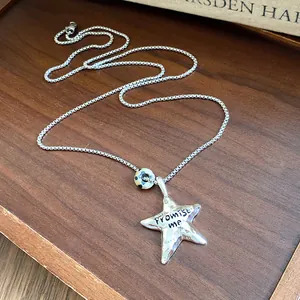Primo piano collana con ciondolo a stella d'argento, metallo stropicciato e Promise me