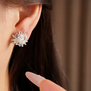 Gros plan de boucles d'oreilles fleur en argent avec zircons bleus et clairs sur l'oreille
