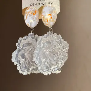 Close-up of translucent resin flower earrings with gold flake oval studs
