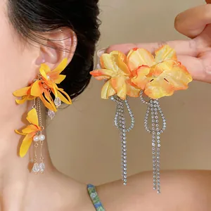 Detail view of fabric flower earrings with sparkling rhinestone tassels and pearls.