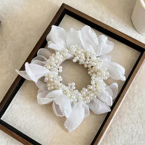 Close-up of elegant white chiffon flower scrunchie with faux pearl bead accents