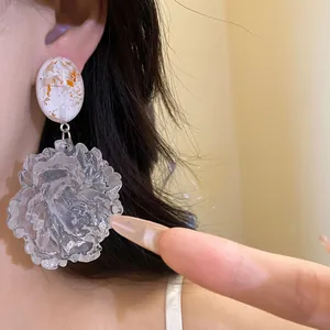 Detailed close-up of vintage resin flower pendant earrings with silver needles and gold flakes.