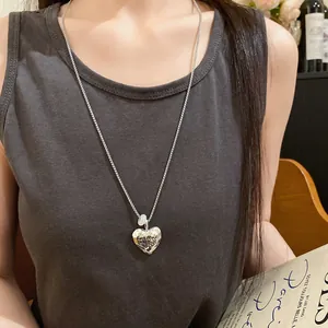 Dettaglio di una collana con ciondolo a cuore in metallo martellato con una piccola perla bianca