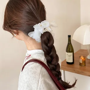 Elegant close-up of white chiffon flower scrunchie with pearls on a braided hairstyle