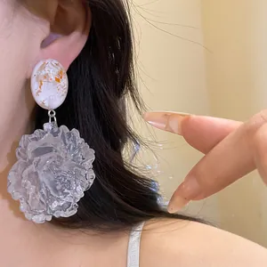 Detailed macro view showing large translucent resin flower pendant earrings with silver needle