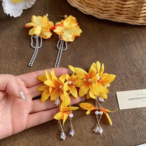 Close-up detail of elegant yellow fabric flower earrings with zircon tassels and pearls