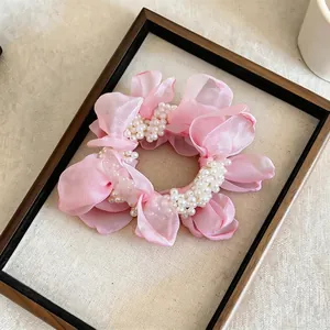 Detailed close-up of a pink chiffon flower scrunchie with elegant white pearl accents