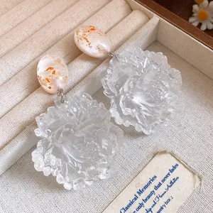 Detailed macro view of elegant translucent resin flower drop earrings with orange flecks