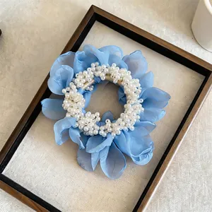 Detailed close-up of a blue chiffon flower scrunchie with white pearl embellishments