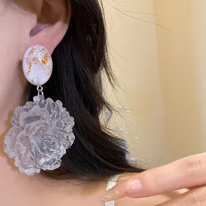 Detailed view of silver needle resin earrings with a large transparent flower pendant.