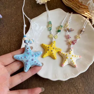 Handmade colorful ceramic starfish necklaces on a shell plate for seaside vacation style