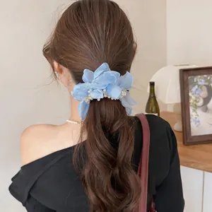 Detailed close-up of an elegant blue chiffon flower scrunchie with pearls on brown hair.