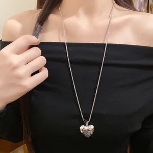 Dettaglio collana con ciondolo a cuore in metallo stropicciato e incisione