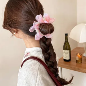Elegant pink chiffon flower and pearl hair scrunchie shown on a braided hairstyle.