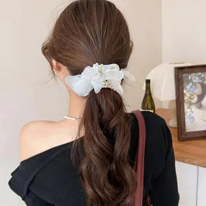Detailed close-up of an elegant white chiffon flower hair scrunchie decorated with pearls