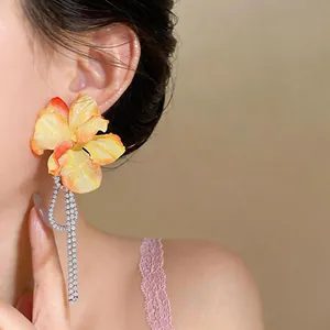 Detailed close-up of yellow fabric flower earrings with sparkling zircon tassels on a model