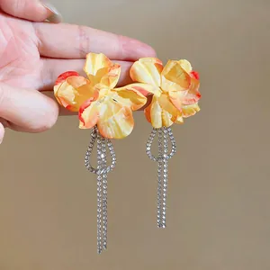 Detail view of fabric flower earrings with long zircon tassels and silver needles.