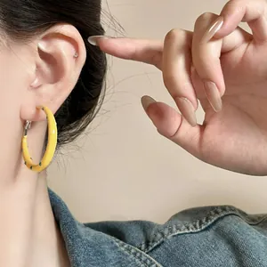 Close-up detail view of yellow enamel hoop earrings with blue polka dot patterns