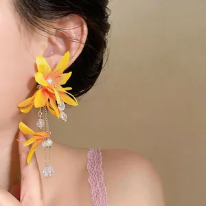 Close-up of yellow fabric flower earrings with elegant bead and chain tassels