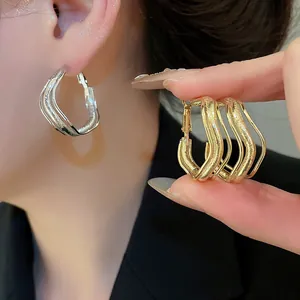 Gros plan de boucles d'oreilles créoles minimalistes à trois couches en or et argent.