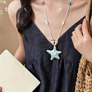 Close-up view of a light blue ceramic starfish necklace with shell details for summer