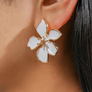 Vista macro de elegante pendiente de flor de esmalte blanco con borde dorado en la oreja