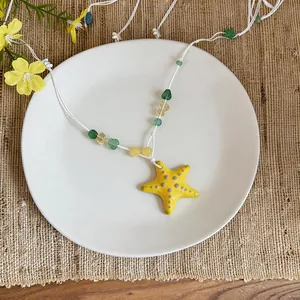 Detailed top view of a yellow ceramic starfish pendant necklace on a white plate