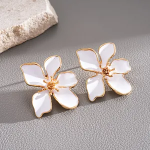 Primer plano de pendientes de flor de esmalte blanco con borde dorado para vacaciones