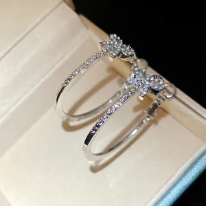 Primo piano di orecchini a cerchio color argento con un delicato fiocco ricoperto di strass.