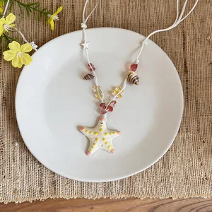 Detail shot of a ceramic starfish pendant necklace with shell and stone beads