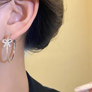Primo piano dettagliato di un orecchino a cerchio argento con fiocco scintillante sull'orecchio