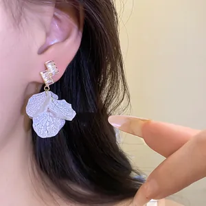 Close-up of elegant flower petal earrings with sparkling zircon studs on model ear