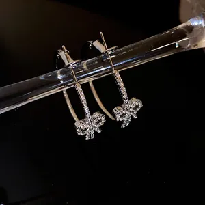 Dettaglio macro di eleganti orecchini a cerchio con fiocco in argento e strass brillanti