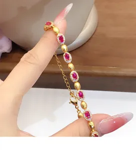 Gros plan d'un élégant bracelet doré avec des zircons rouges ovales et des cristaux