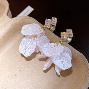 Detailed macro view of white textured flower earrings with zircon and pearl accents