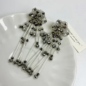 Exquisite silver needle flower tassel earrings with metallic beads on a white plate