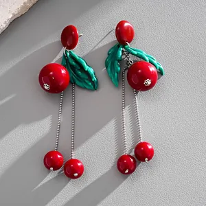Detailed close-up view of vibrant red resin cherry earrings with green leaves and silver tassels
