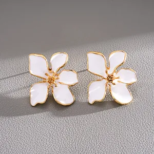 Detalle macro exquisito de pendientes de flor en esmalte blanco con bordes dorados