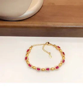 Gros plan d'un élégant bracelet en or avec des zircons rouges ovales et pavé.